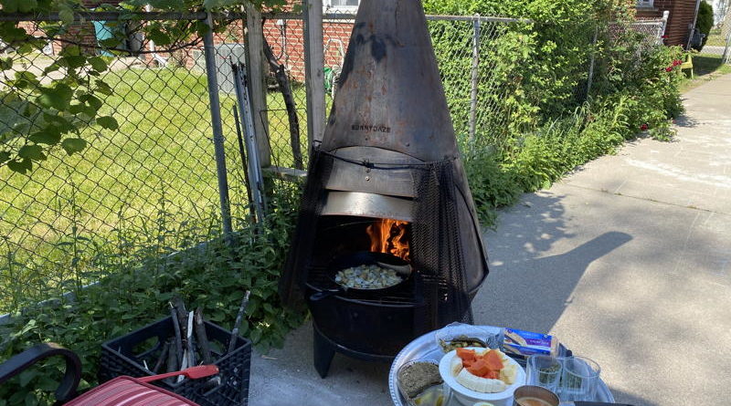 Outdoor chiminea grilling with food on a nearby table.
