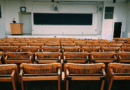 Empty classroom with wooden chairs and a chalkboard.