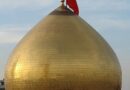 Golden dome with a red flag on top against a clear sky.