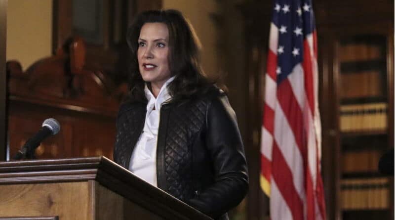 A woman speaks at a podium with an American flag behind her.