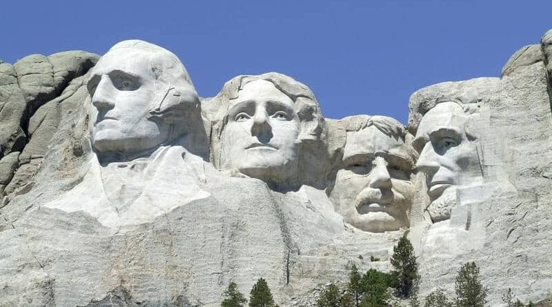 Mount Rushmore with carved faces of four US presidents against a clear blue sky.