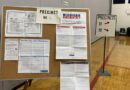A precinct board displays voter information and instructions inside a polling station.