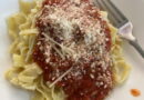 A plate of pasta with rich tomato sauce and grated cheese.