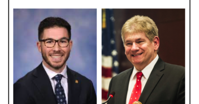 Two professional men, one in glasses and suit, the other in suit and red tie, smiling for photos.