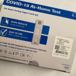 COVID-19 at-home test kit with a test strip showing results.