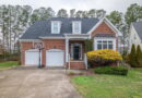 A brick house with a two-car garage and a manicured front yard.