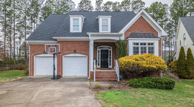A brick house with a two-car garage and a manicured front yard.