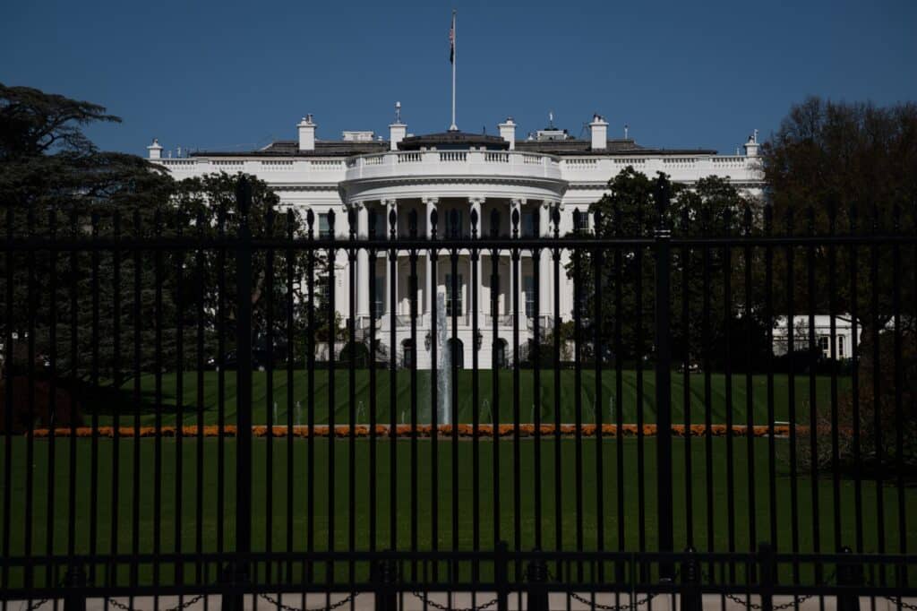 The White House behind a black fence on a clear day.