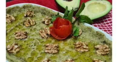 A dish garnished with walnuts, a carved tomato, and avocado halves.