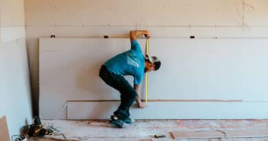 Man crouching indoors, touching the floor in a casual pose.
