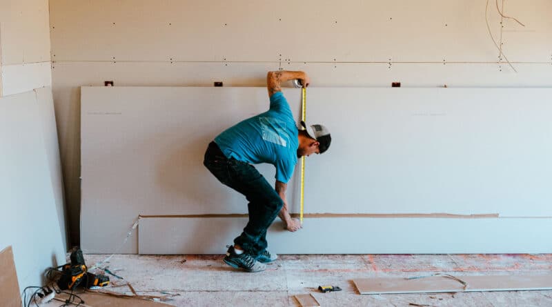 Man crouching indoors, touching the floor in a casual pose.