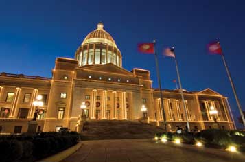 Illuminated government building with dome and flags at night.